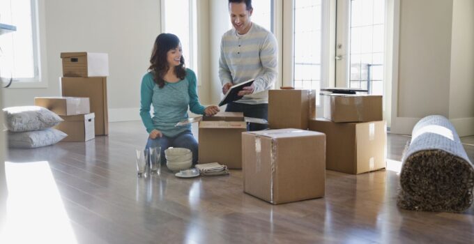 Couple unpacking cardboard boxes in new home