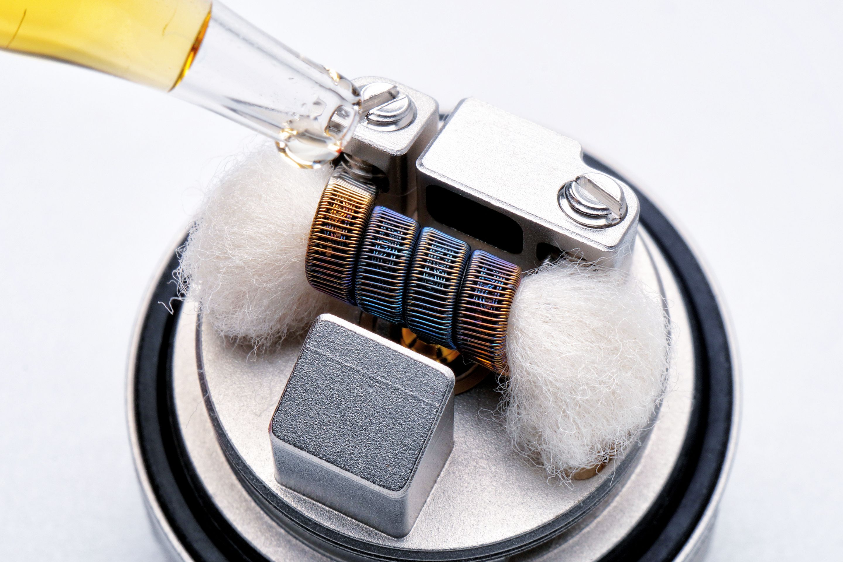 Macro shot of a vape atomizer coil being primed, showing the heating element technology that preserves flavor at low temperatures