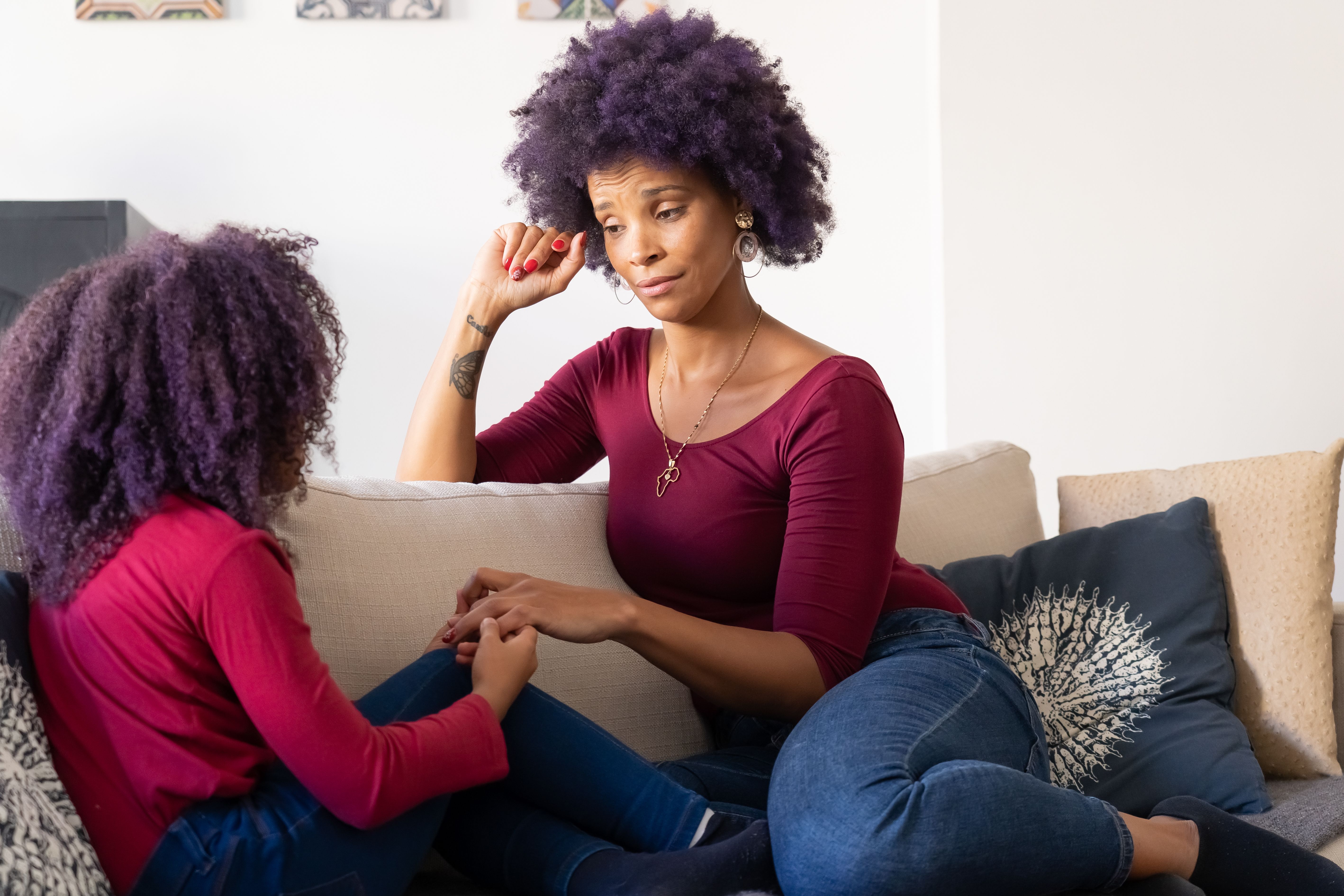 Mother and daughter holding hands on a couch, sharing a quiet moment of bonding and connection