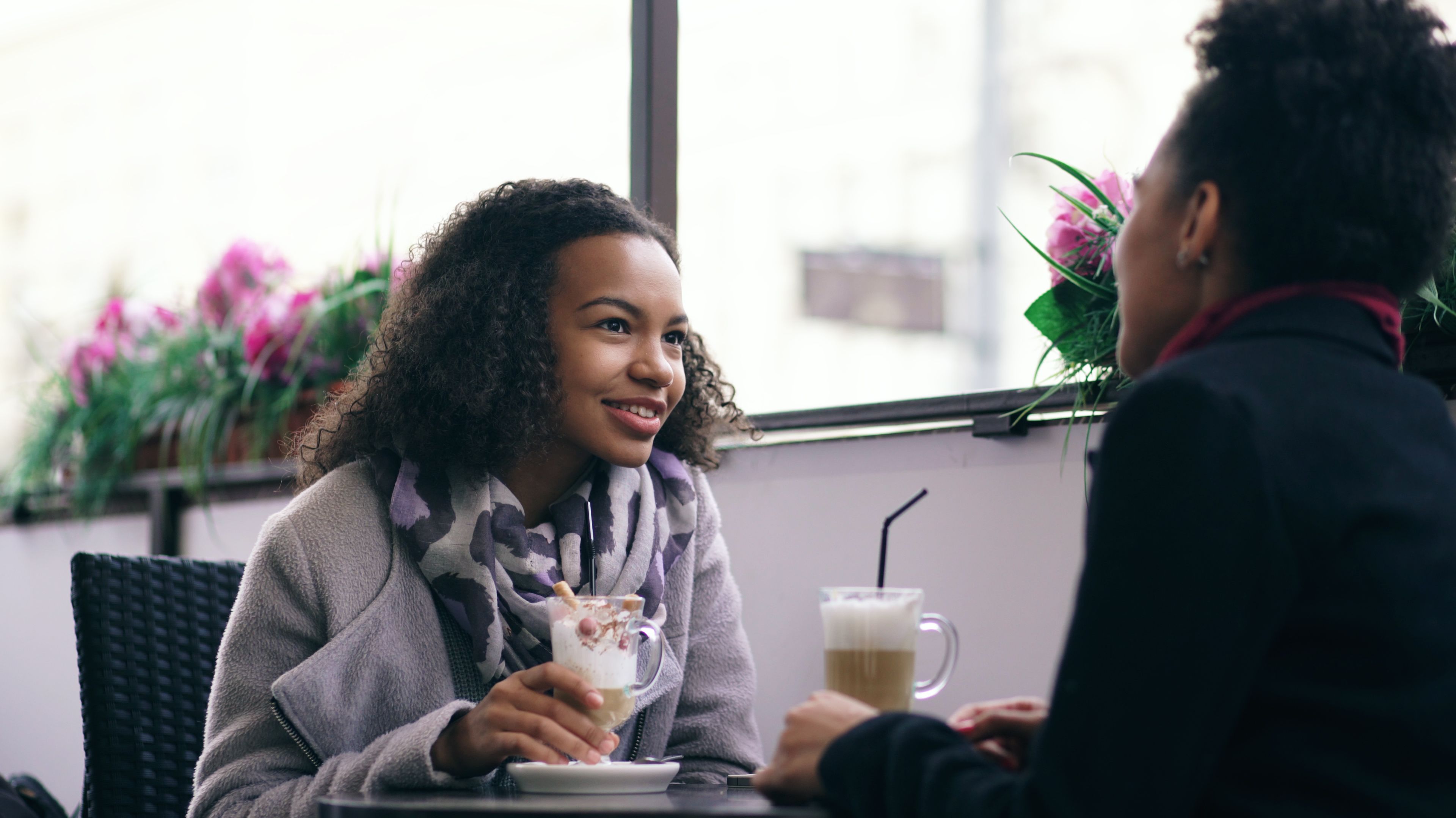 Two women having a real, present conversation over coffee at a cozy cafe