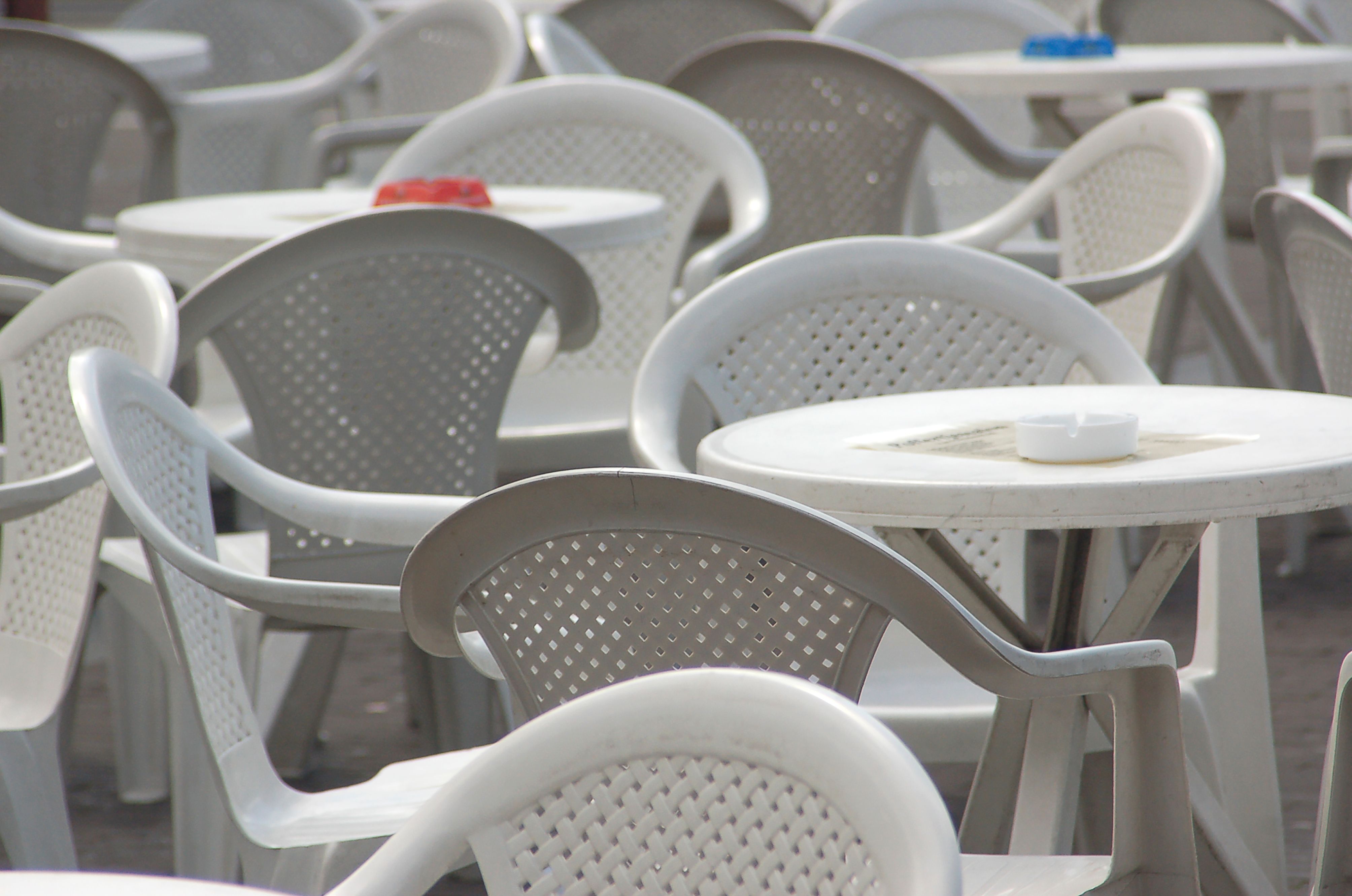 White plastic outdoor chairs and tables arranged in an open seating area, illustrating a lightweight plastic furniture option.